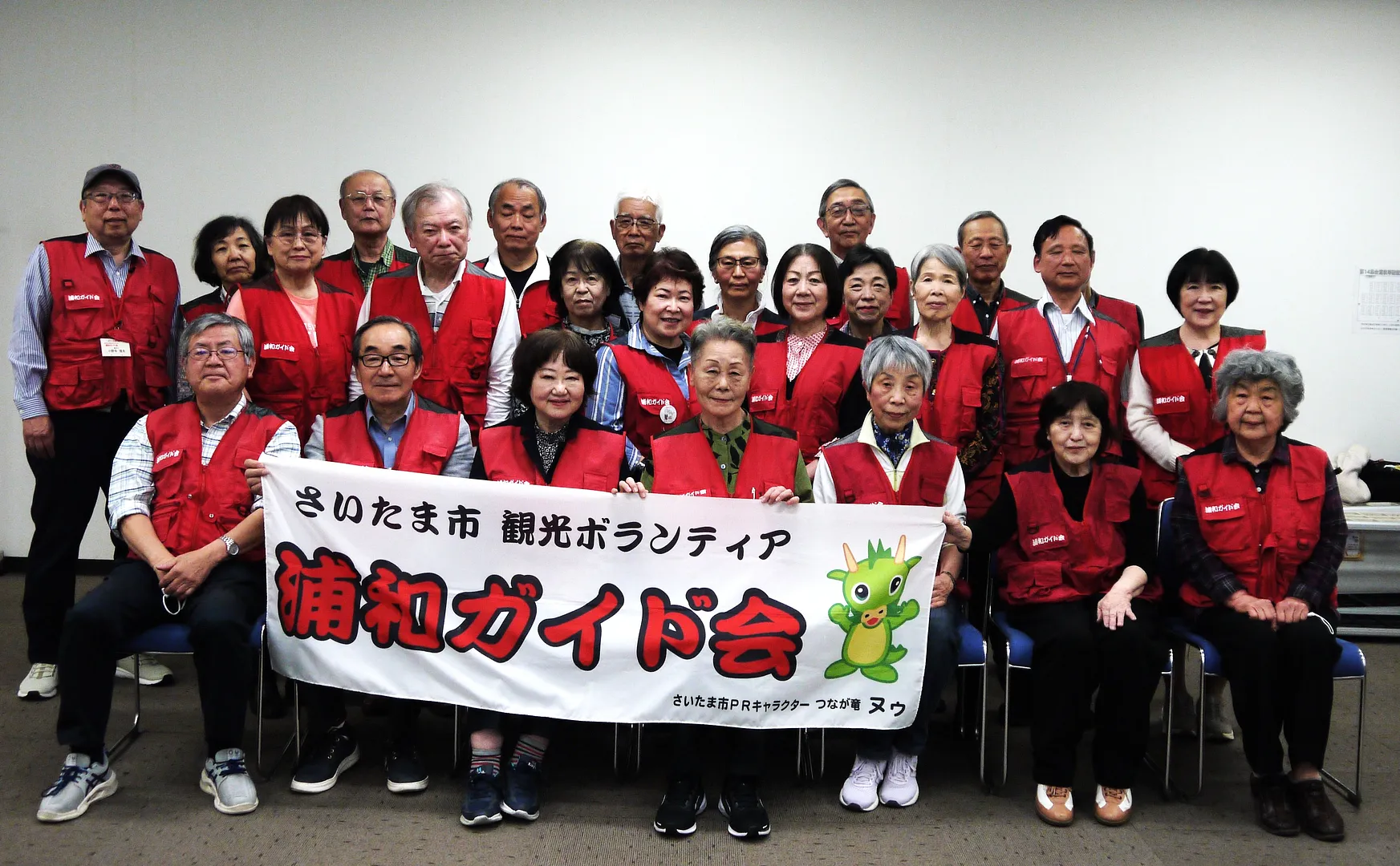 お揃いの赤いベストを着た浦和ガイド会メンバーの集合写真