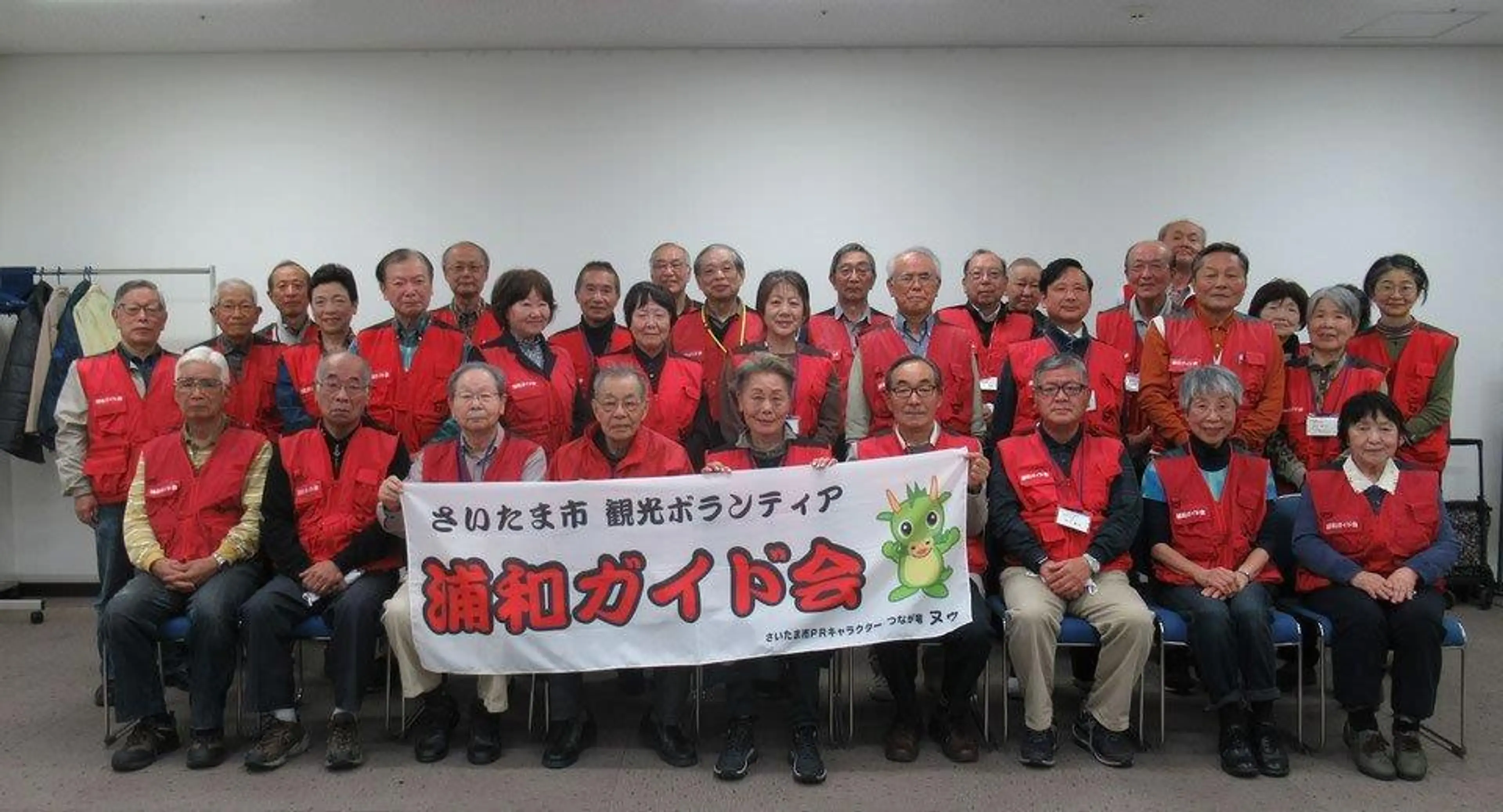お揃いの赤いベストを着た浦和ガイド会メンバーの集合写真